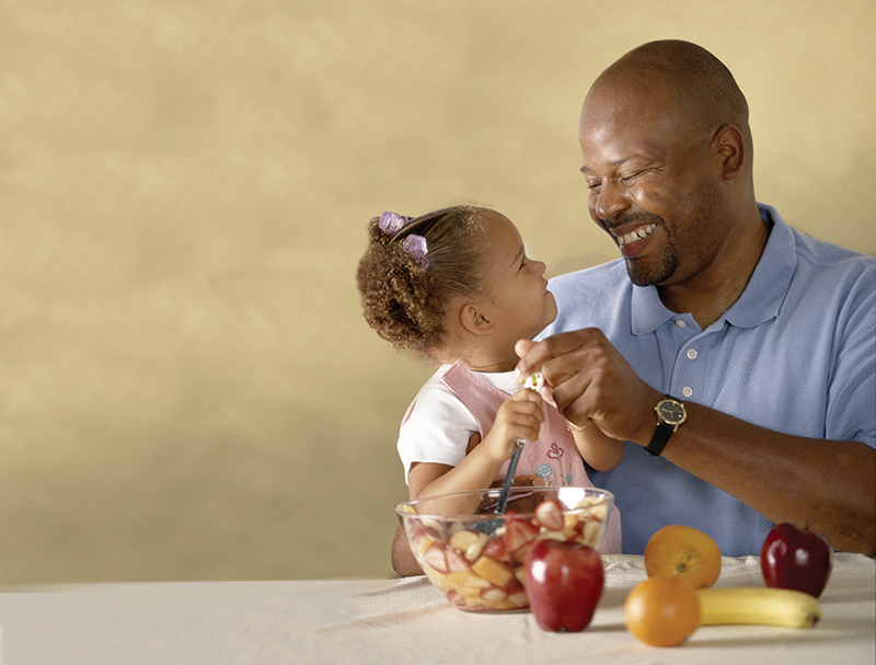 Man sharing healthy food with little girl.