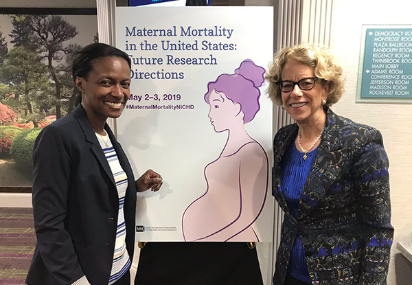 Cynthia Giamfi-Bannerman, M.D., of Columbia University, and Diana Bianchi, M.D., NICHD Director, standing near a poster for NICHD’s Maternal Mortality workshop.