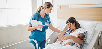 Un médico al lado de la cama de una persona que recientemente ha dado a luz con una mano sobre los ojos, sosteniendo al recién nacido.