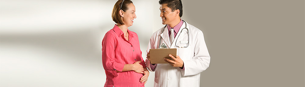 A pregnant woman smiling and talking to a doctor.