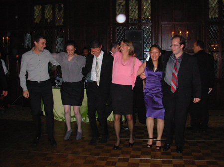 Lab members dance in a line while wearing suits and dresses.