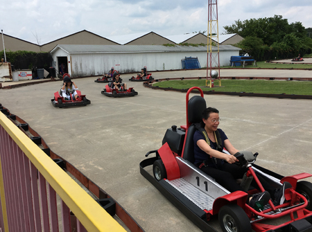 Lab members driving red and black go karts around a track.