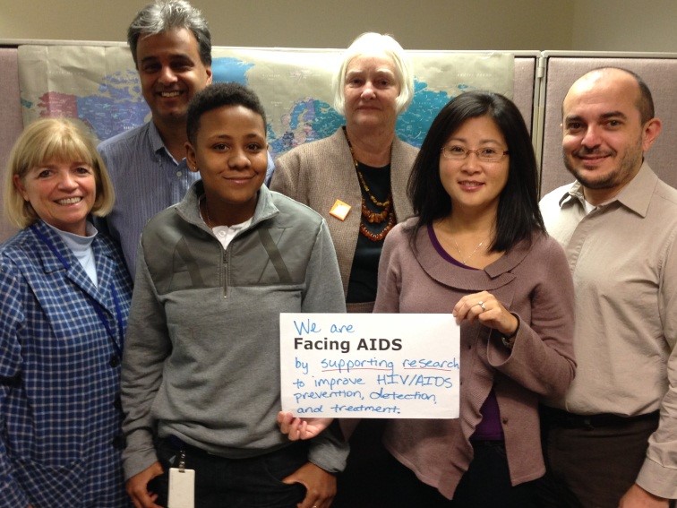 Dr. Rohan Hazra (back row, far left) poses with other NICHD researchers who focus on HIV/AIDS for the #FacingAIDS campaign. Their sign reads: We are #FacingAIDS by supporting research to improve HIV/AIDS prevention, detection, and treatment.