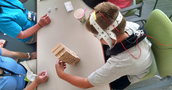 Boy fitted with brain stimulation headgear used in the study manipulates blocks.