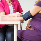 Pregnant woman sitting and having her blood pressure taken by a health care provider