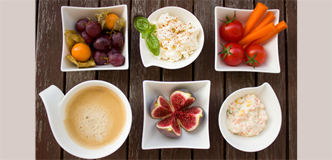 Photograph of fruits, vegetables, and other food arranged in small, white dishes.