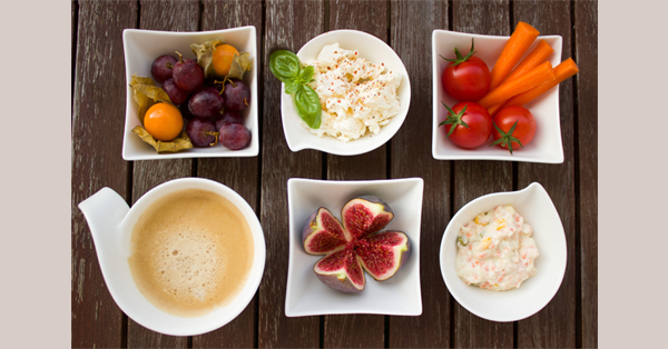 Photograph of fruits, vegetables, and other food arranged in small, white dishes.