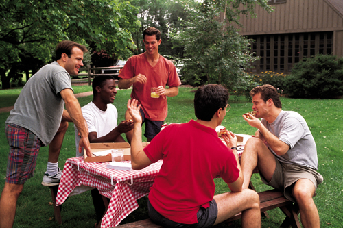 Group of young men sitting around a picnic table and talking