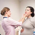 Health care provider feels the neck of a pregnant woman to check her thyroid gland