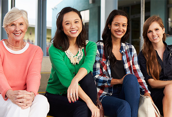 Four women sitting on the steps in front of an office building