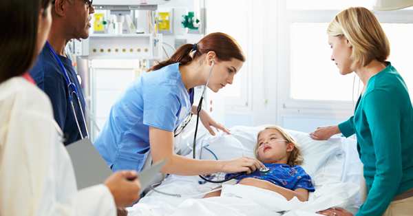 Hospital staff attend to a child in bed in the pediatric intensive care unit, while the child’s mother stands by the bed