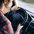 Young man in front of steering wheel, driving a car