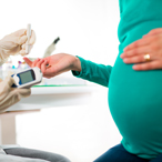 Pregnant woman offering her finger to healthcare provider for a blood test.