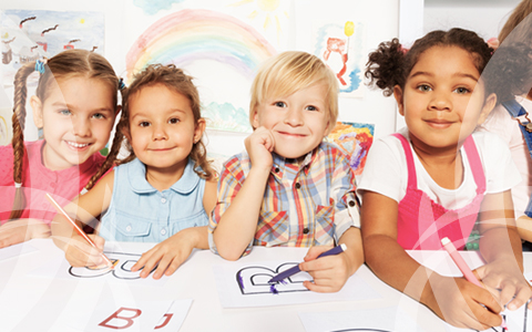 Four children smiling and coloring