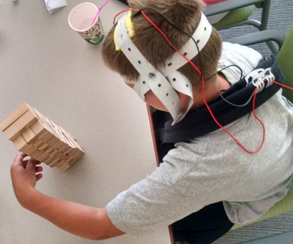 Image of a boy with cerebral palsy during a therapy session where he wears a device that provides a mild electrical current to his brain