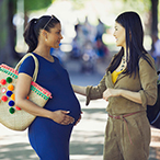 Pregnant woman talking to a woman who does not appear to be pregnant.
