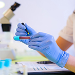 A lab tech labels a test tube containing a blood sample.