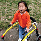 Young girl with cerebral palsy using a walker to move independently.