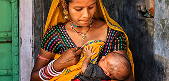 A young Indian mother breastfeeding her newborn baby.