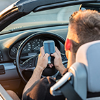 Youth texting behind wheel of a car.