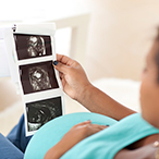 Pregnant woman looking at printout of pregnancy scans.