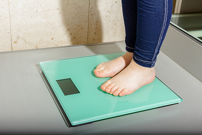 A child’s feet and ankles on a bathroom scale.