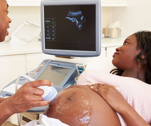 Medical professional performing ultrasound on pregnant woman in a doctor’s office. 