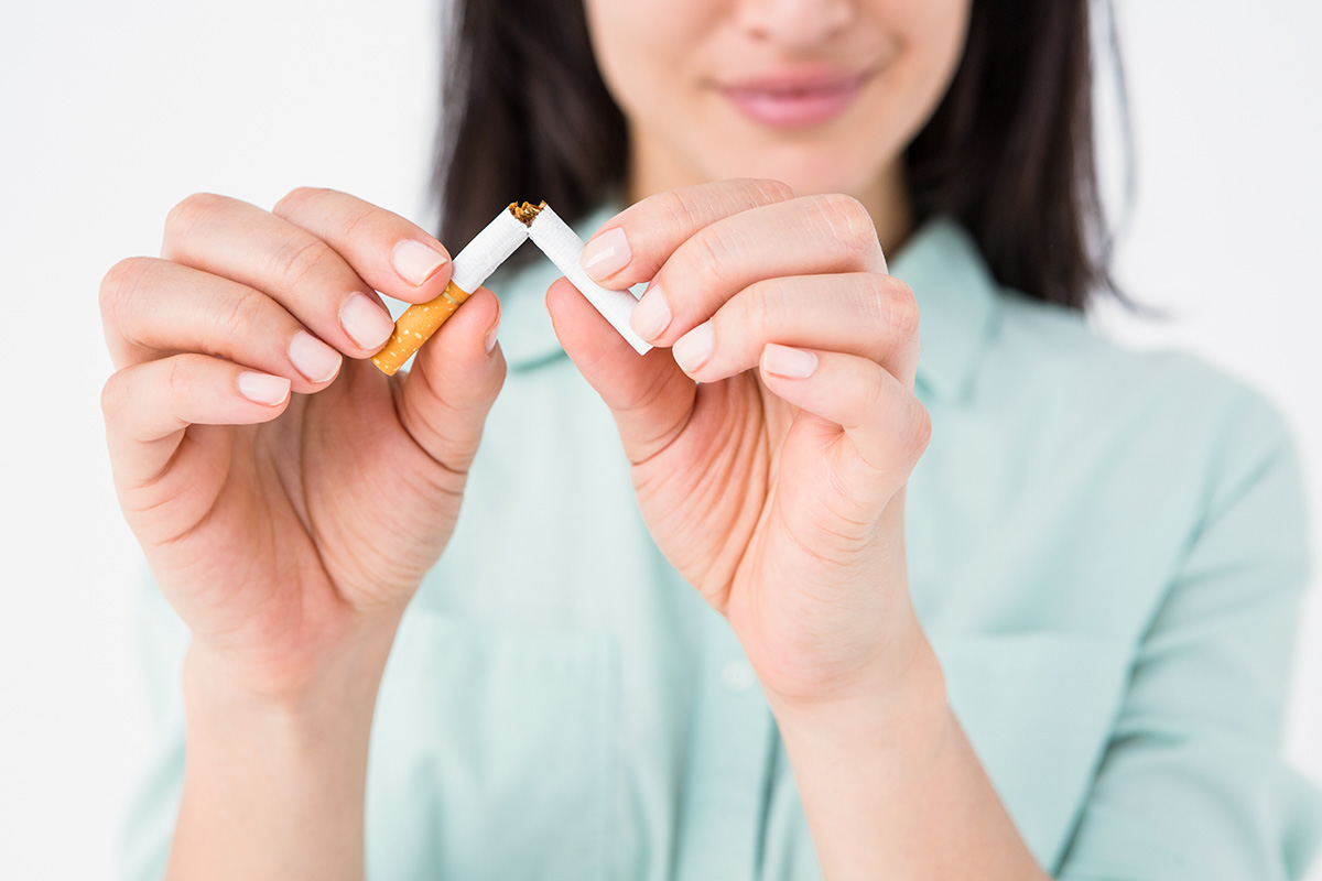 Woman holding unlit cigarette that has been broken in half 