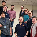 Members of the Dasso lab are standing along both sides of a staircase, four on the left and five along the right.