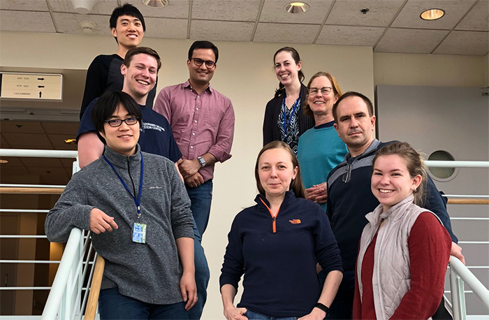 Members of the Dasso lab are standing along both sides of a staircase, four on the left and five along the right.