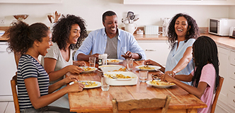 Parents with adolescent children seated at kitchen table.