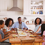 Parents with adolescent children seated at kitchen table.