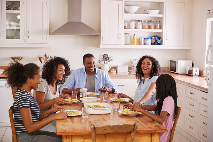 Parents with adolescent children seated at kitchen table.