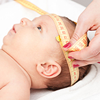 Infant having his/her head circumference taken with a tape measure.