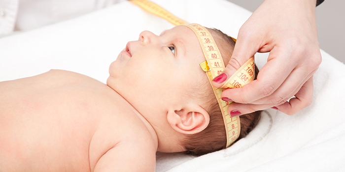 Infant having his/her head circumference taken with a tape measure.