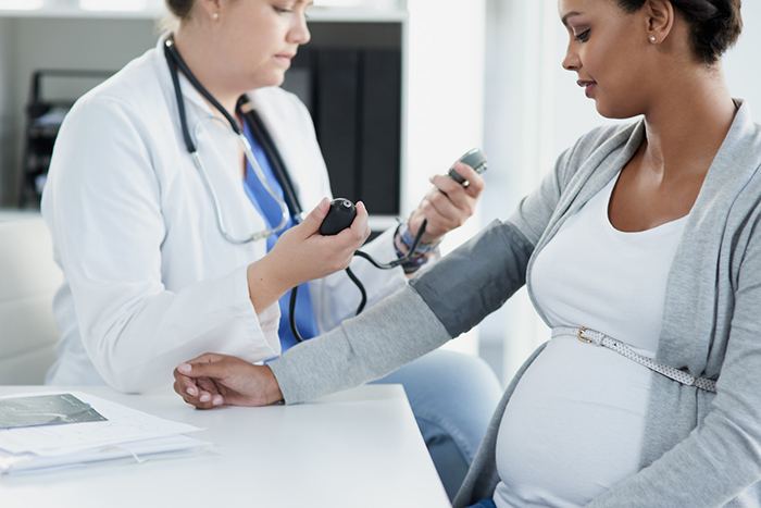 A female doctor takes the blood pressure of a pregnant woman.