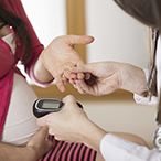 Pregnant woman holding her hand out for a healthcare worker to test her blood sugar test.