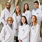 Dr. Bianchi and her lab members are all wearing white lab coats and standing in two rows on a staircase.