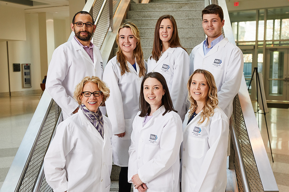 Dr. Bianchi and her lab members are all wearing white lab coats and standing in two rows on a staircase.