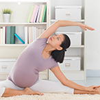 Pregnant woman on mat doing yoga.