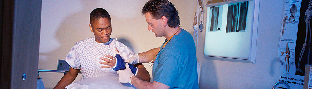 A healthcare provider examining a young adult male patient with a cast on his wrist.