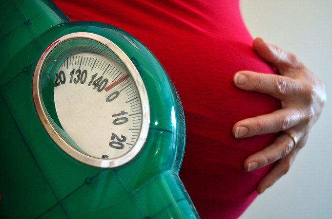 Pregnant woman holding belly with her hand.