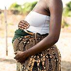 Side view of pregnant woman’s torso, hands on abdomen.