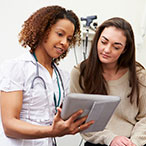 Nurse and woman looking at screen on a handheld tablet.