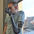 Man drinking from a cup with left hand prosthetic.
