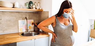 Stressed pregnant woman standing in kitchen.