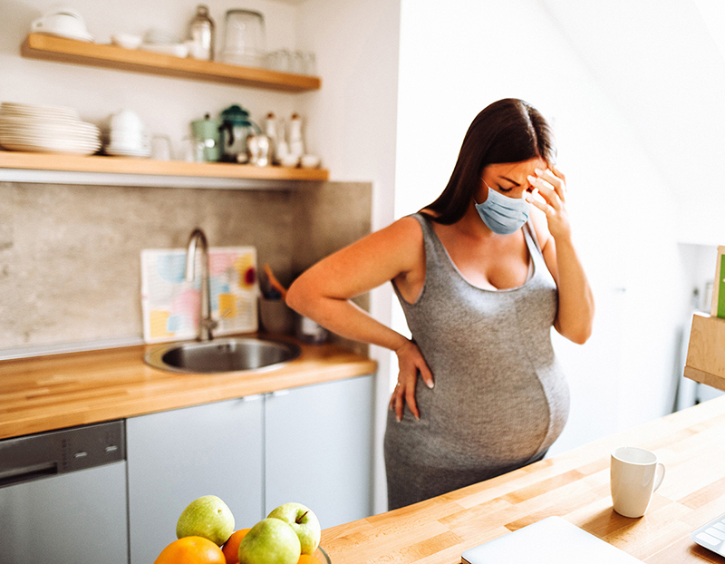 Stressed pregnant woman standing in kitchen.