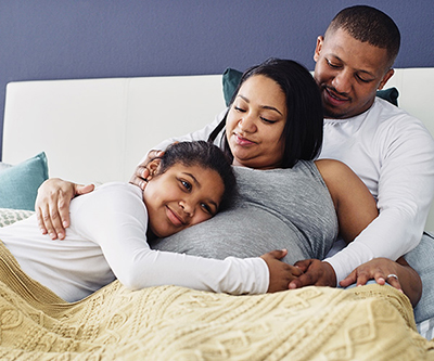 A smiling child hugging her mother and holding hands with her father.