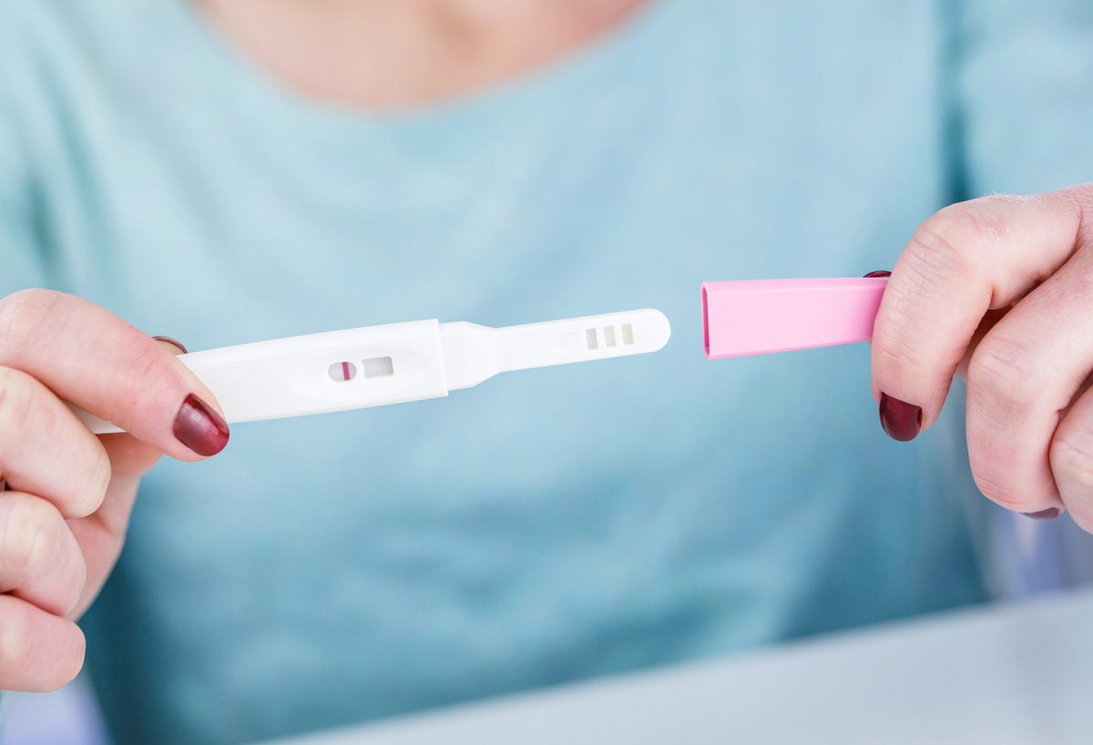 Woman’s hand’s holding at-home pregnancy test strip 