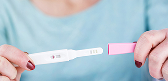 Woman’s hand’s holding at-home pregnancy test strip 